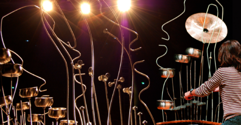 Femme jouant sur une sculpture sonore en formes de visages.
