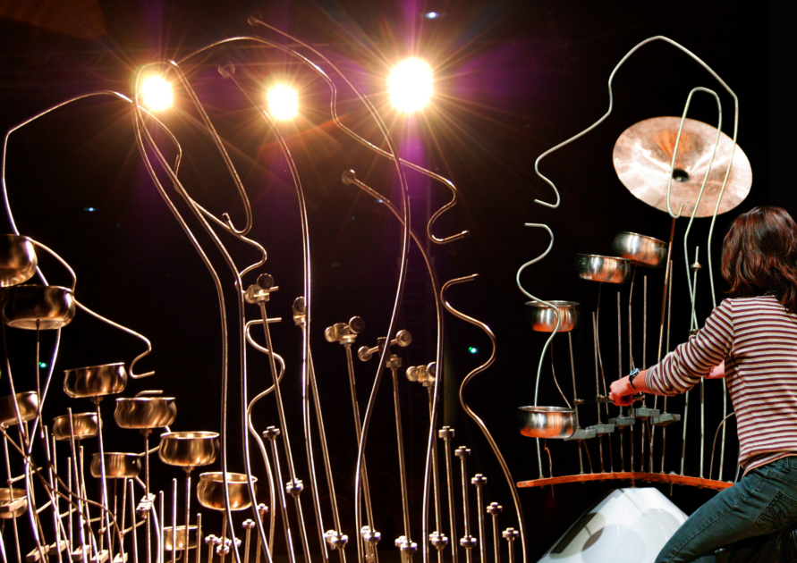 Femme jouant sur une sculpture sonore en formes de visages.