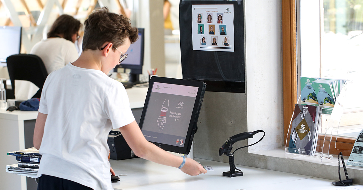Enfant à l'automate de prêts de la médiathèque de La Parenthèse.